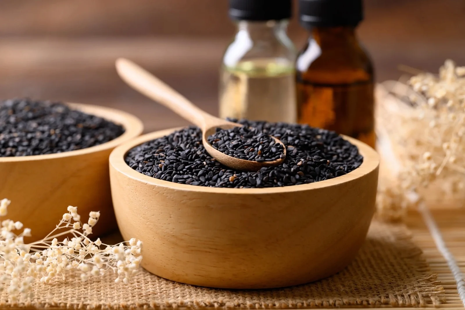 Black sesame seeds in wooden bowls with a wooden spoon