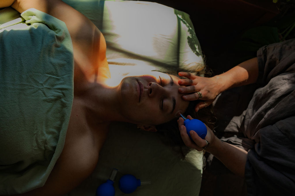 Taylar providing facial cupping during a treatment