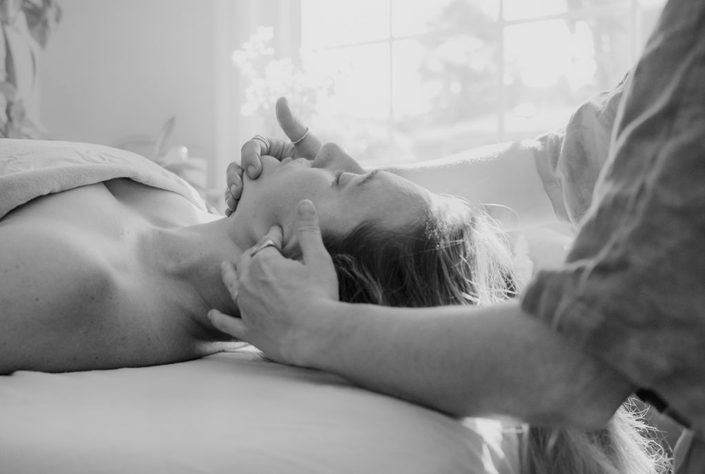 Black-and-white photograph of Taylar gently massaging a patient’s face