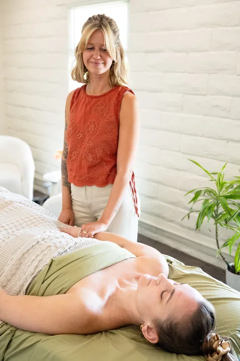 Kristy checking a patient’s wrist during treatment at Evoke