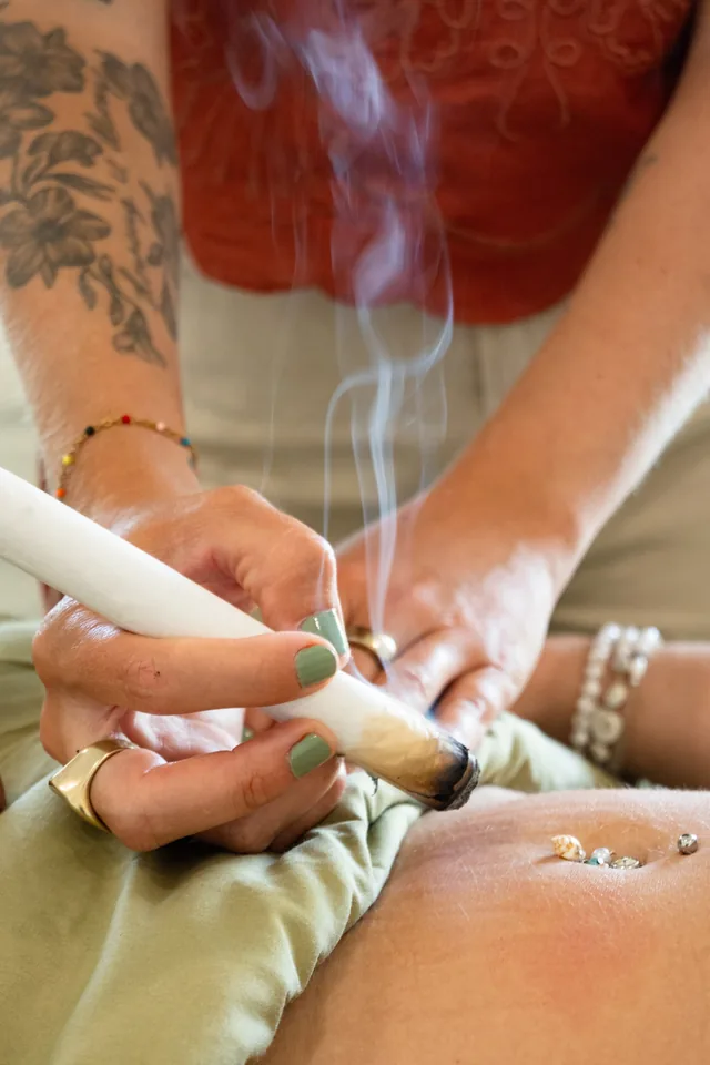 Practitioner holding a smoking moxa stick near a patient’s abdomen