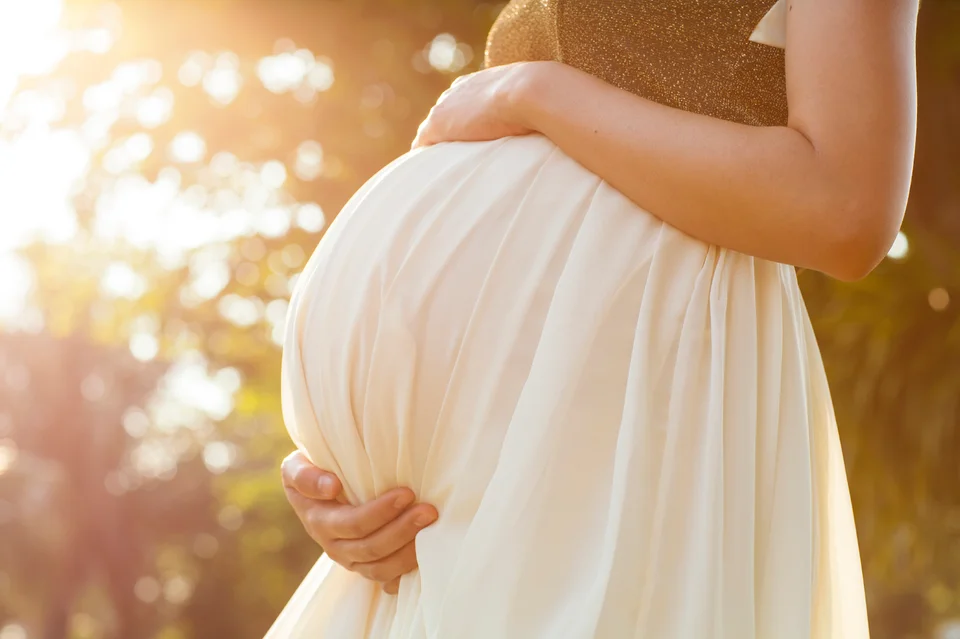 An expectant mother cradling her belly in warm sunlight